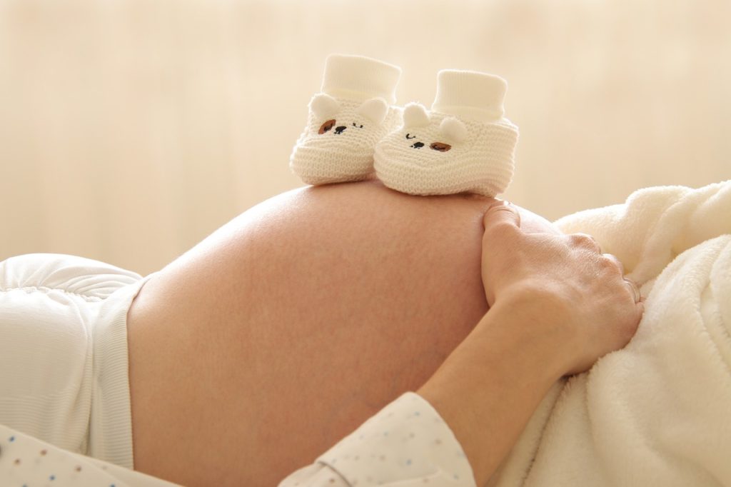 chaussons de bébé posés sur le ventre de femme enceinte